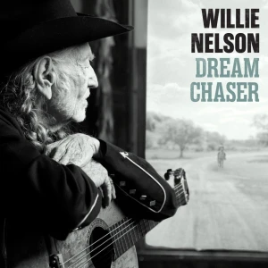Side-profile of an elderly man with a cowboy hat and guitar, gazing out a window; poster to the right reads 'WILLIE NELSON DREAM CHASER'.