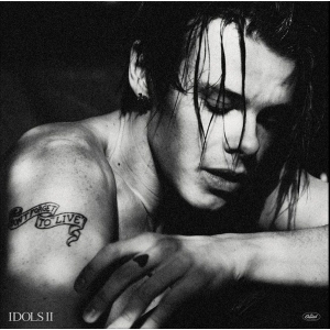 Black-and-white portrait of a shirtless person with wet hair, arm resting, tattoo reads 'Don’t Forget to Live' and album label 'IDOLS II' in corner