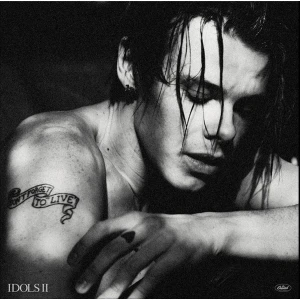 Black-and-white portrait of a shirtless person with wet hair, arm resting, tattoo reads 'Don’t Forget to Live' and album label 'IDOLS II' in corner
