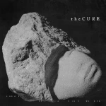 Album cover with a rough rock formation against a black background and 'the Cure' text in the upper right.
